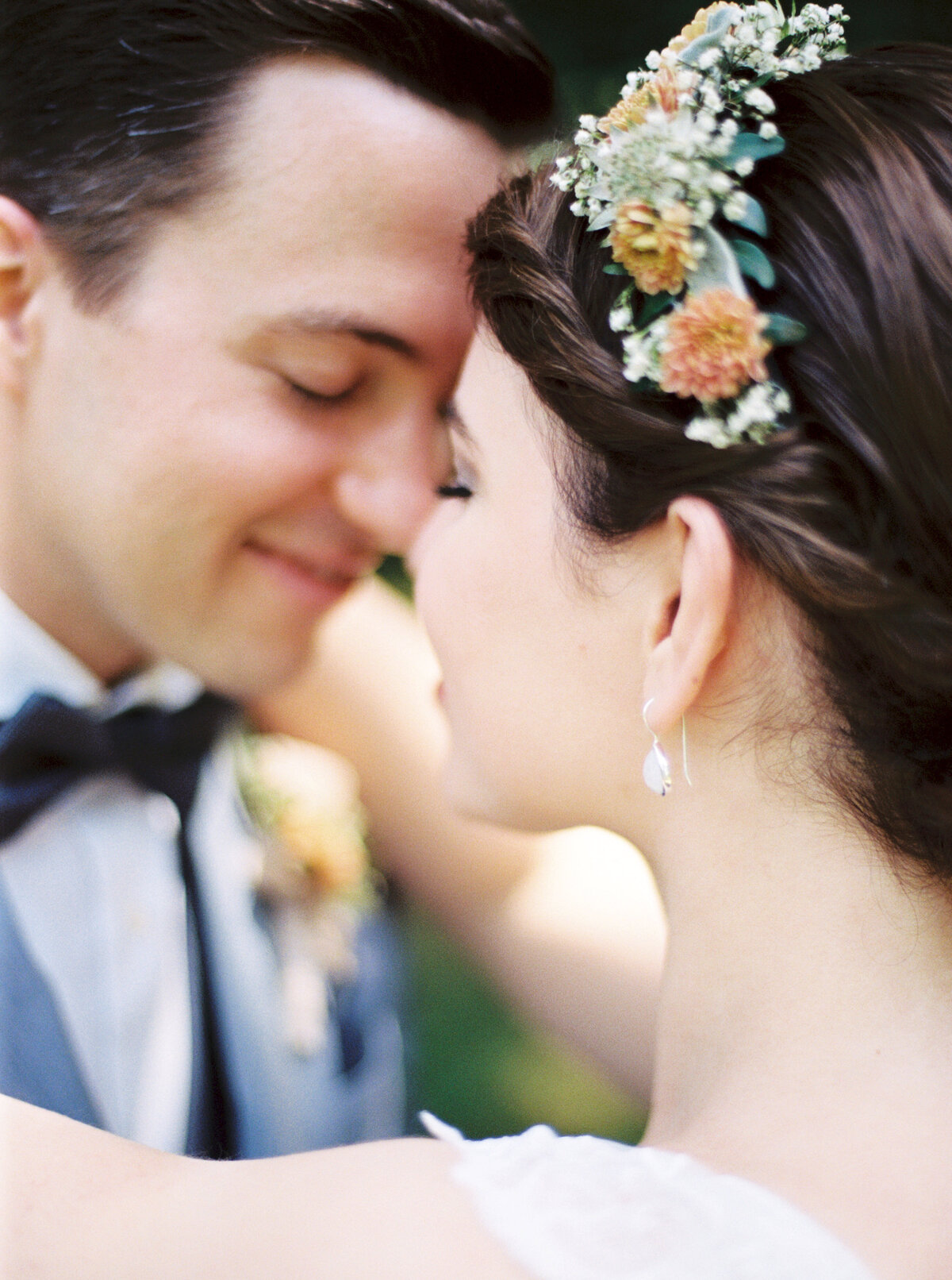 bride and groom smile while standing forehead to forehead