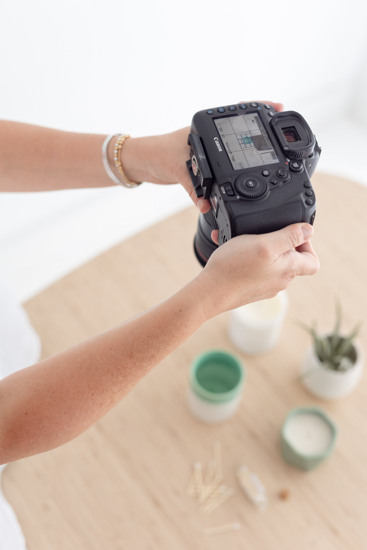 overhead view of kassady holding a canon camera during a product photoshoot of candles