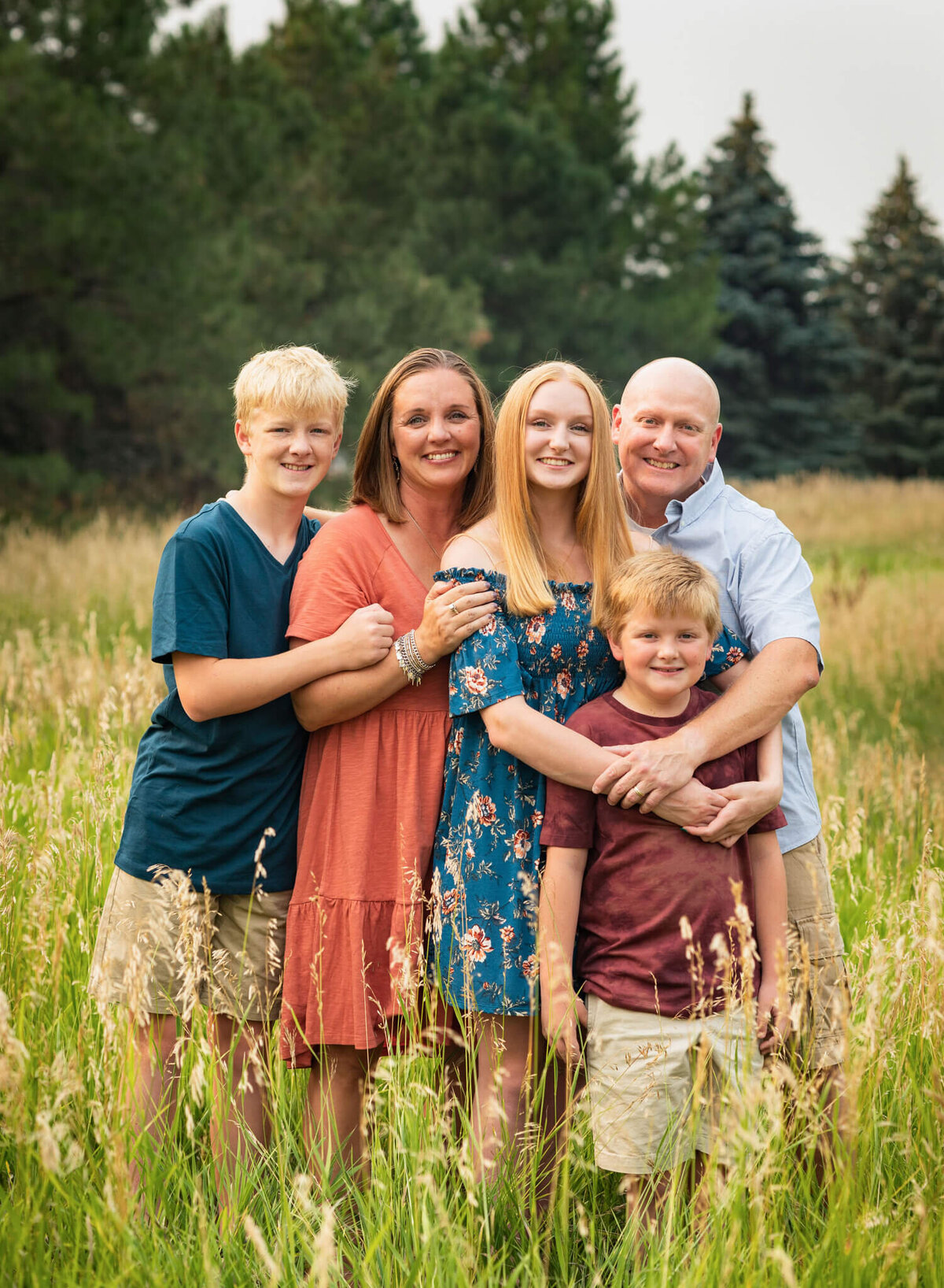 family of five standing close together in a field