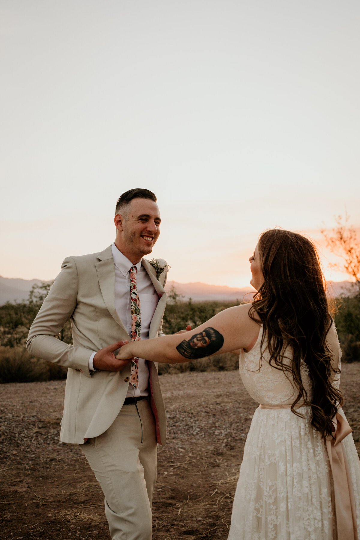 bride and groom dancing silly in the desert at sunset