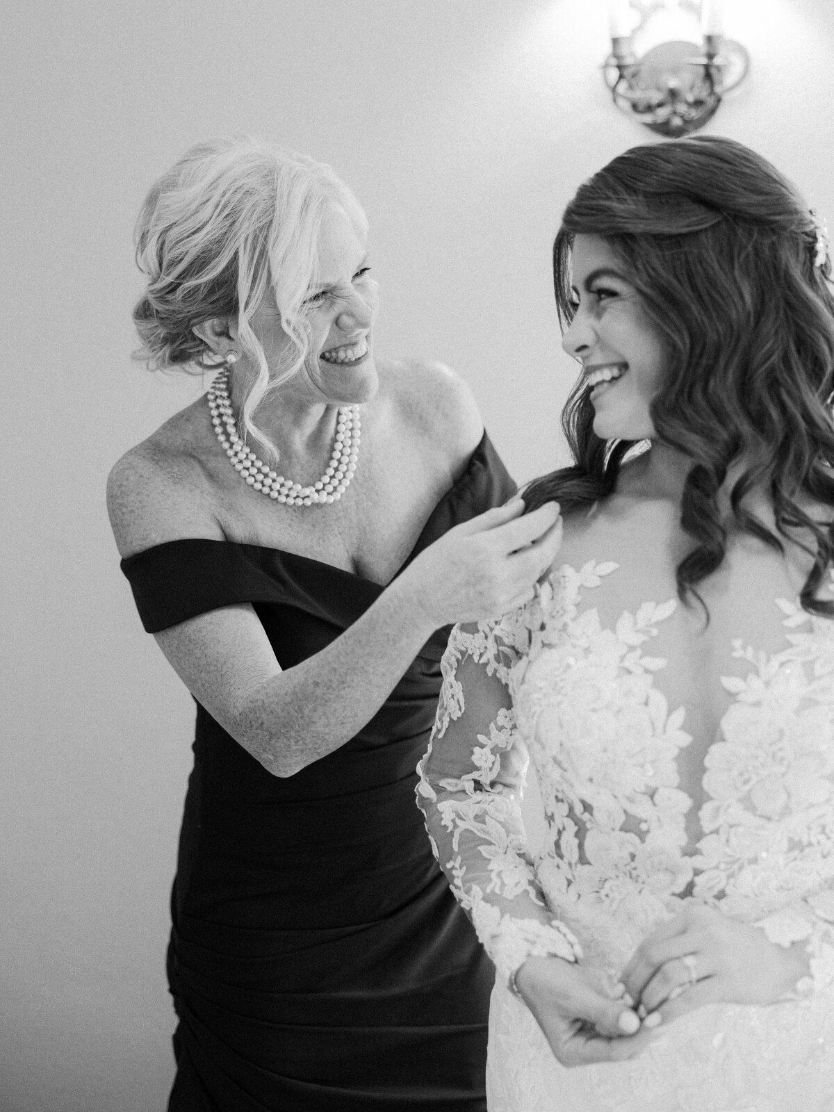 A touching moment between a bride and her mom as her mom helps to get the bride into her wedding dress