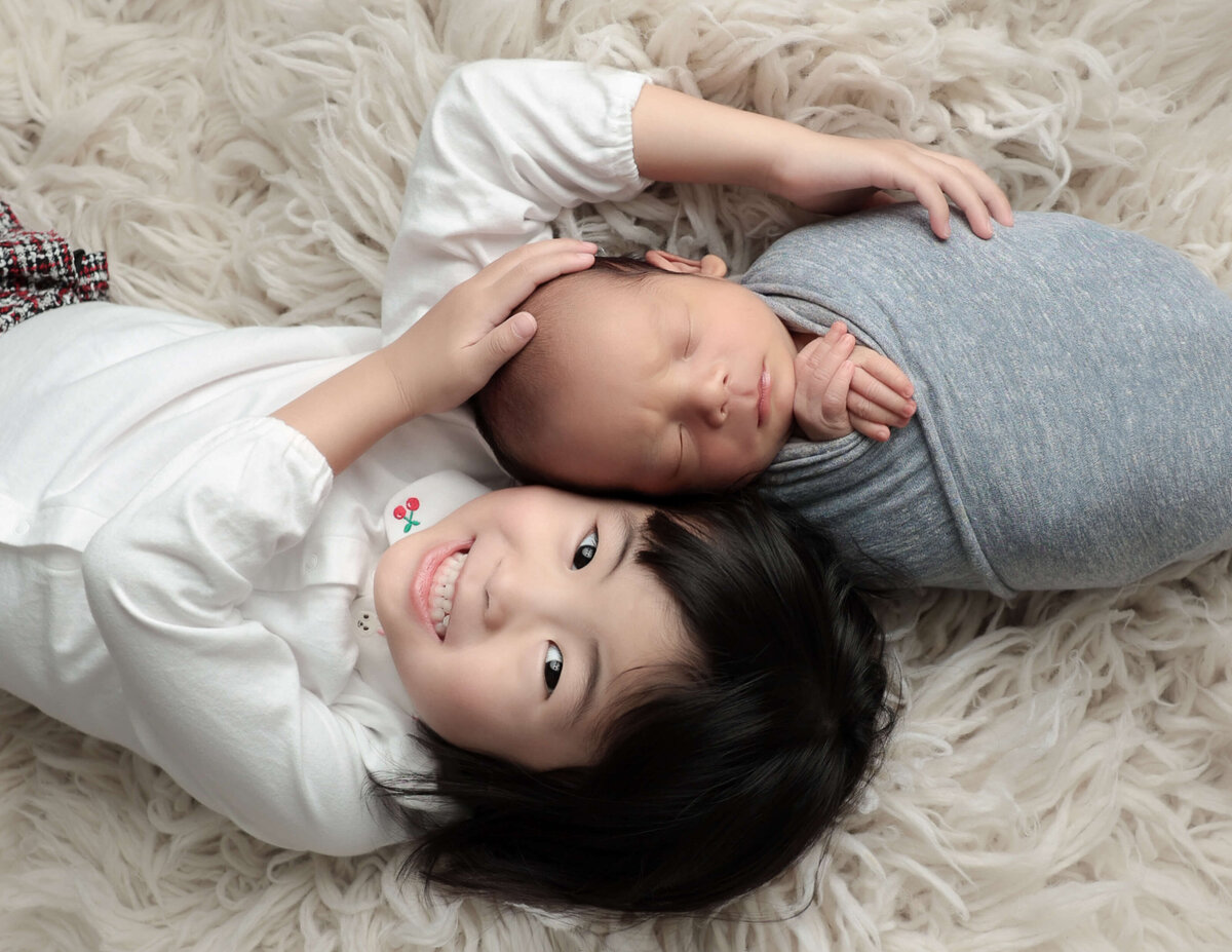 Baby boy posed with big sister at our in-home Rochester, NY studio.