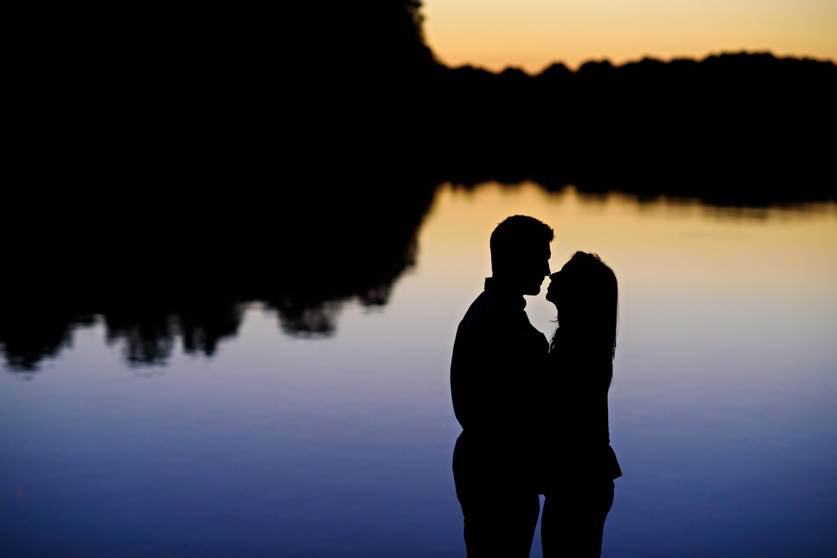 A silhouette of an engaged couple at sunset on a lake in Delaware.