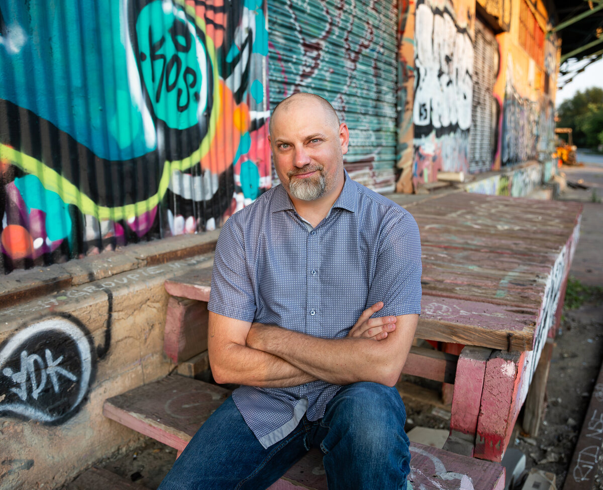 A small business owner poses with graffiti in Baltimore, Maryland during his branding photoshoot.