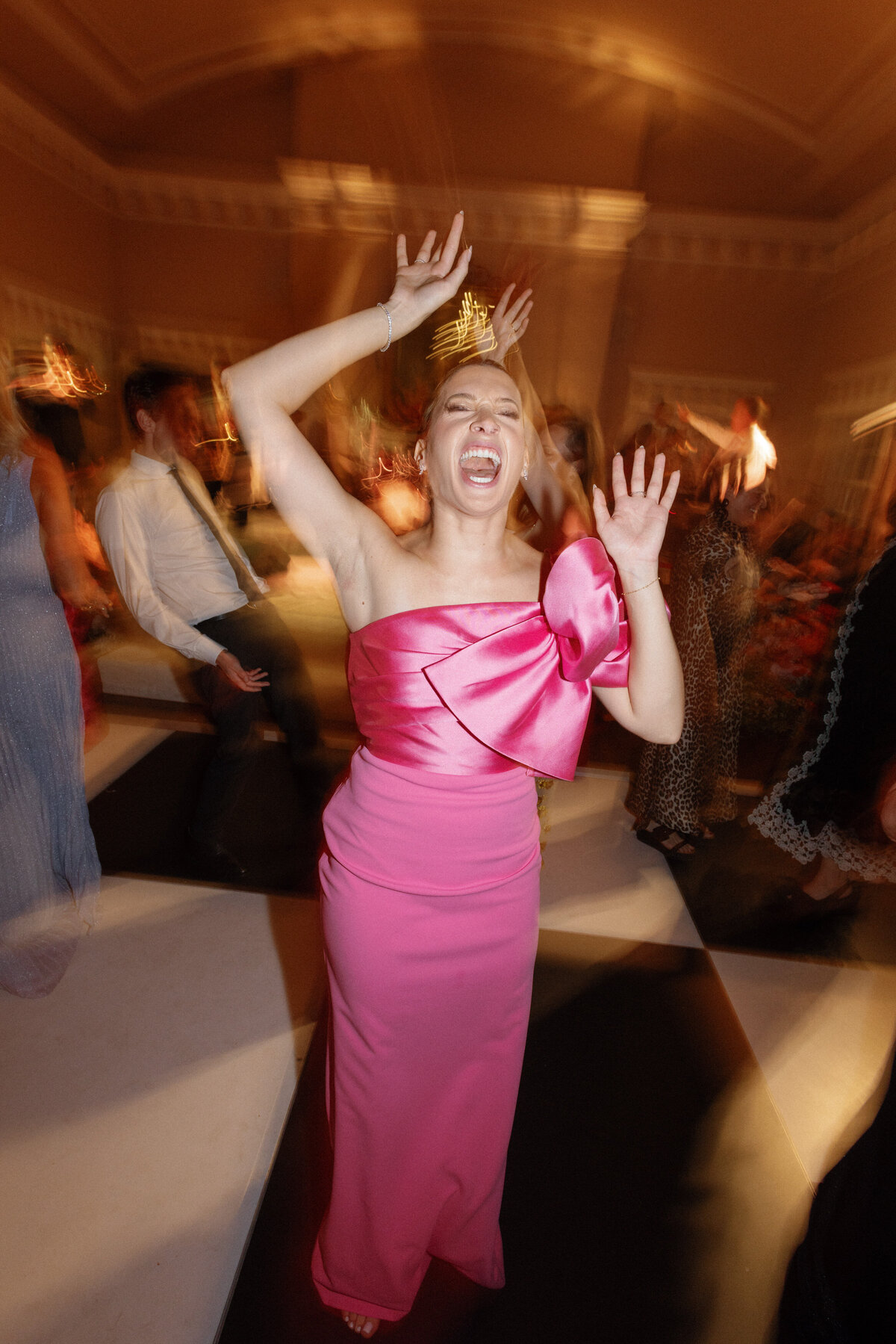 Dancing wedding guest in pink bow dress