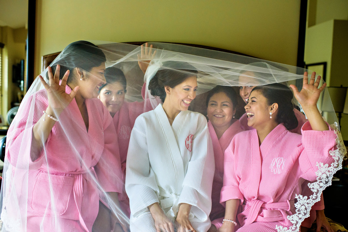 A bride and her bridesmaids under the veil in her parents home before the wedding.
