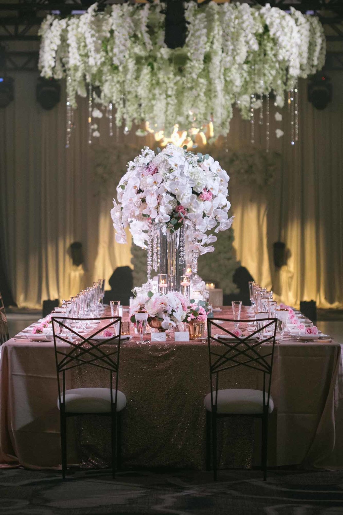 Tall white and blush floral arrangements line the head table at this luxe Indian Fusion wedding