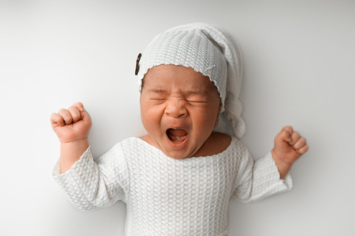 Studio newborn yawn pose on a white backdrop