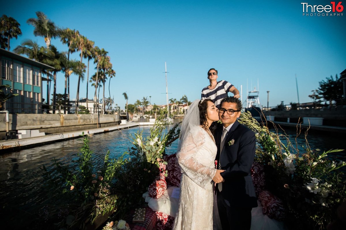Bride kisses her Groom on the cheek as the Gondolier steers the vessel through the Long Beach channels