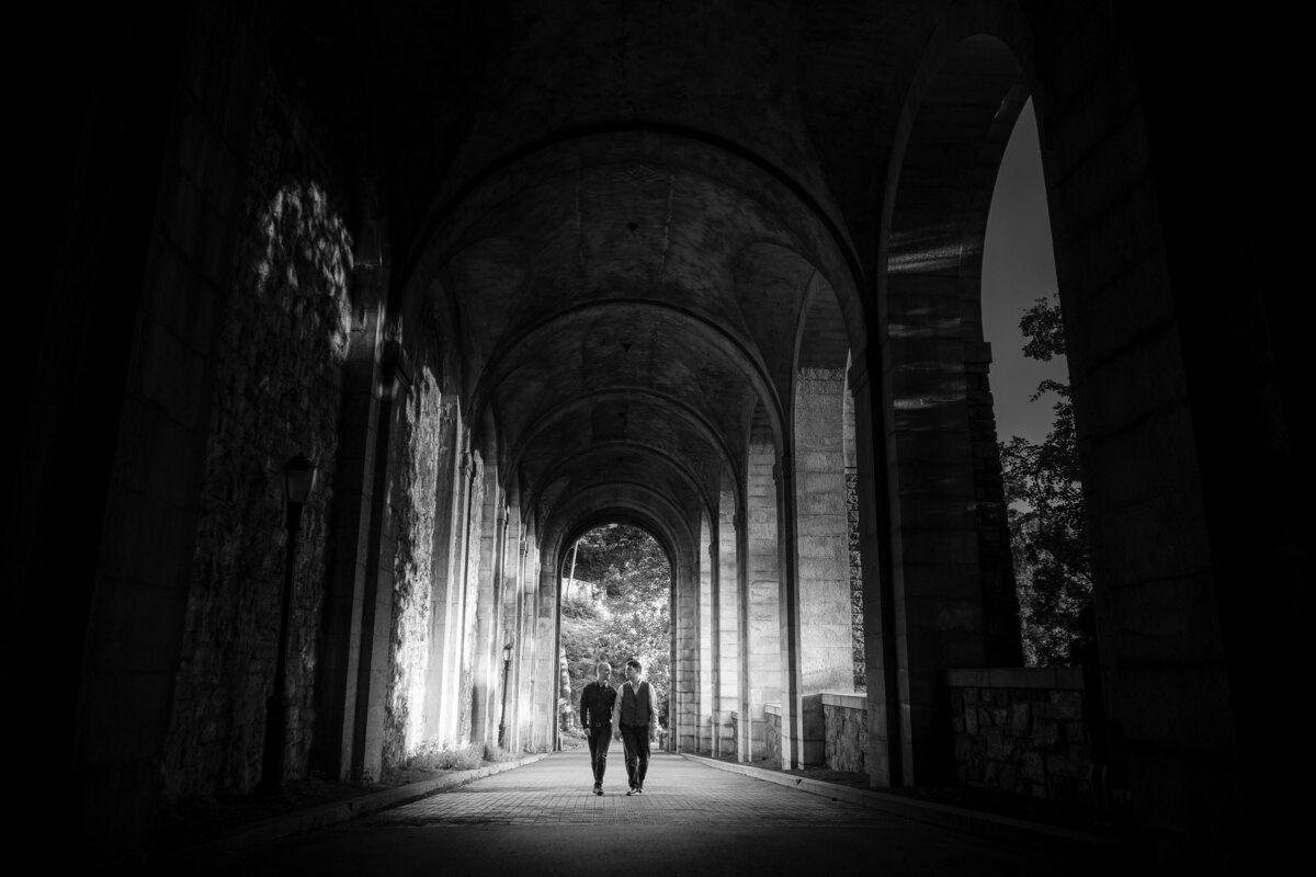 A couple walking through a large arched walkway.