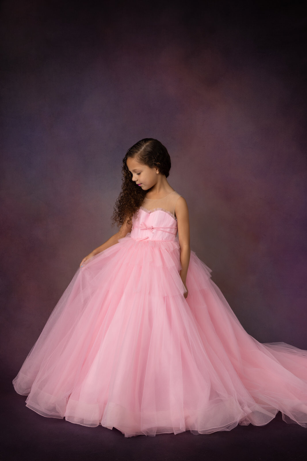 girl-in-pink-dress-holding-skirt-looking-down-in-studio