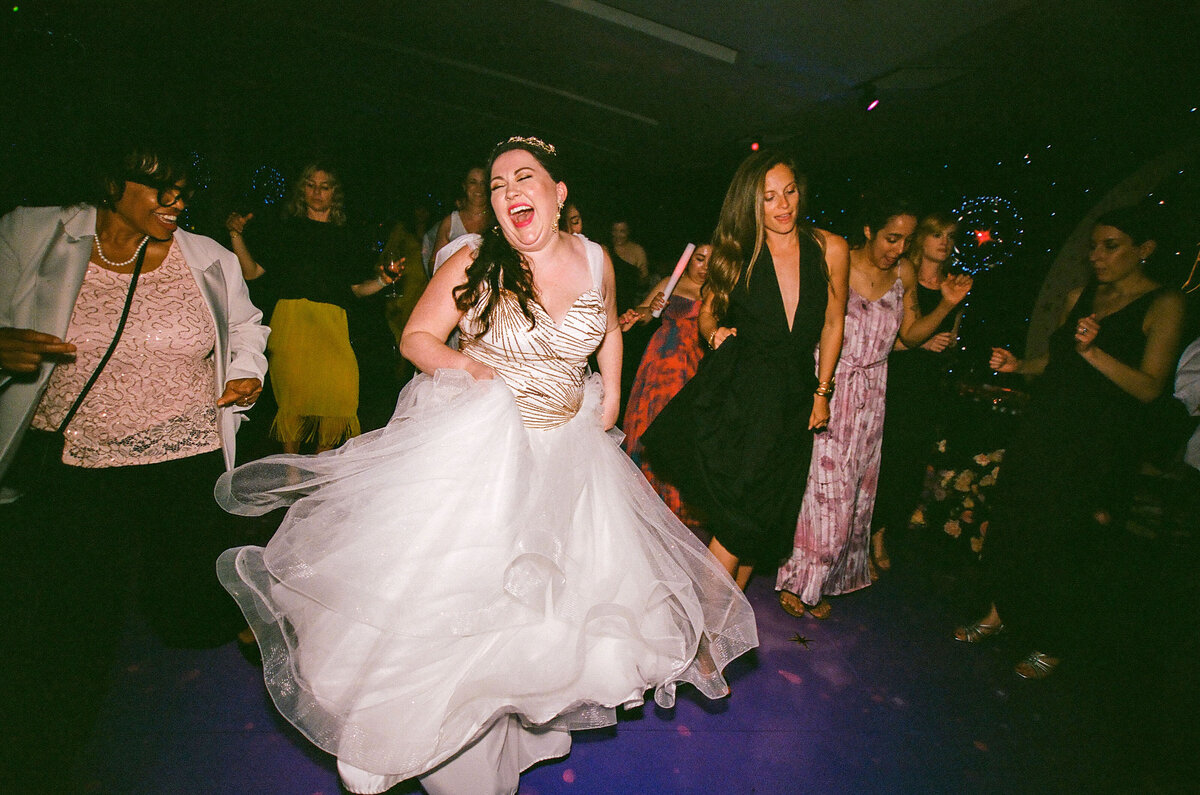 A bride dancing with her guests at a reception.