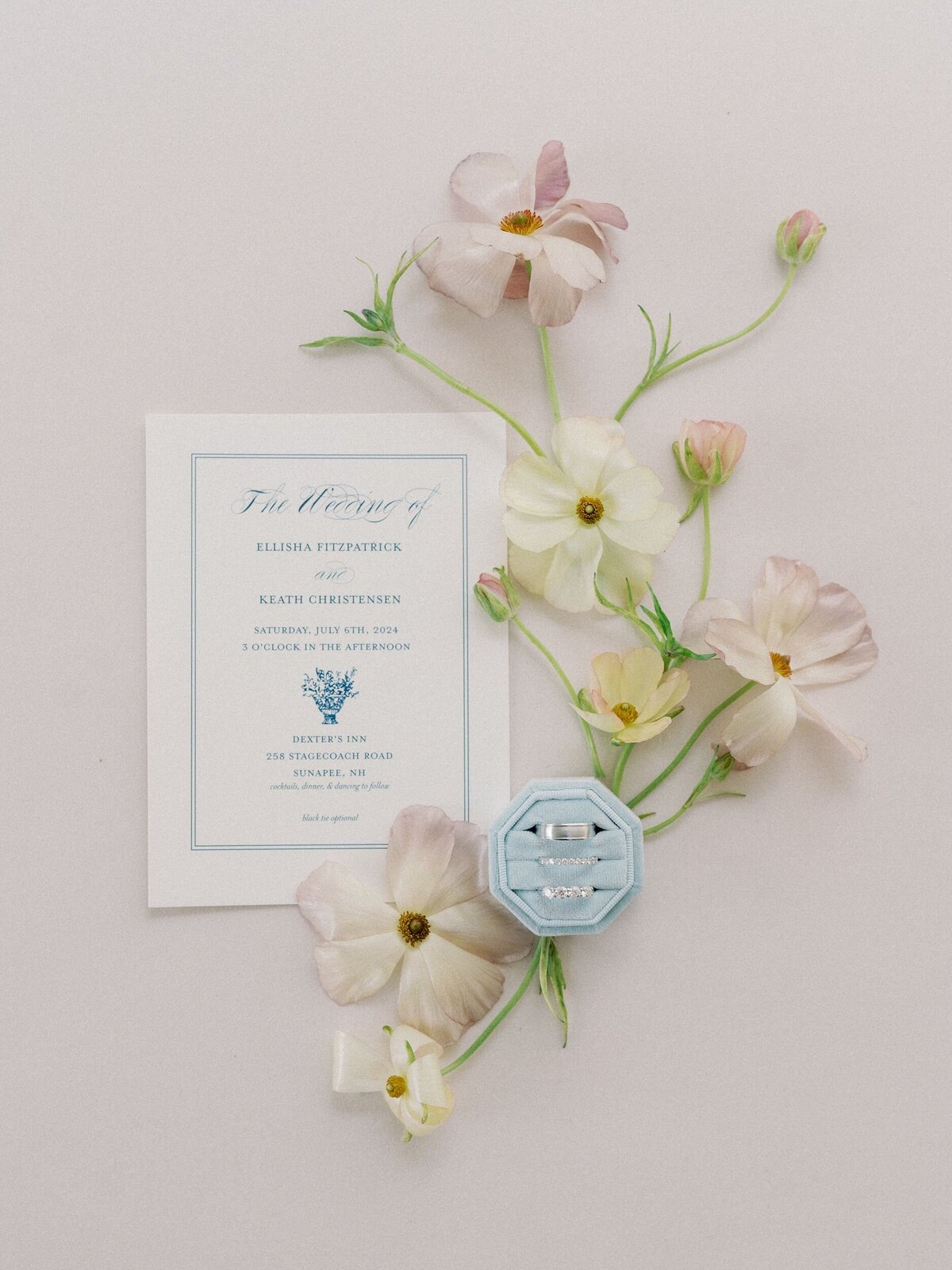 Invitation flatlay with wedding rings and florals