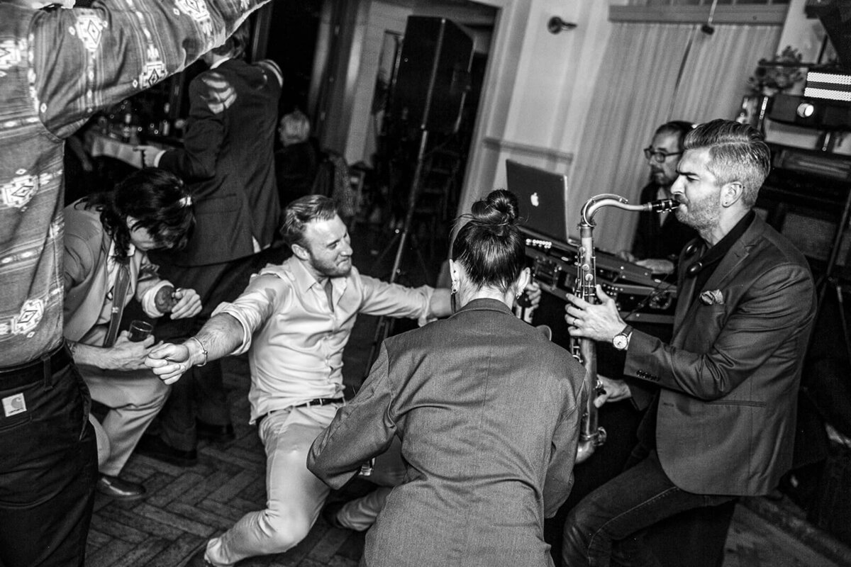 Guests dancing to saxophonist at wedding reception at Thames Rowing Club