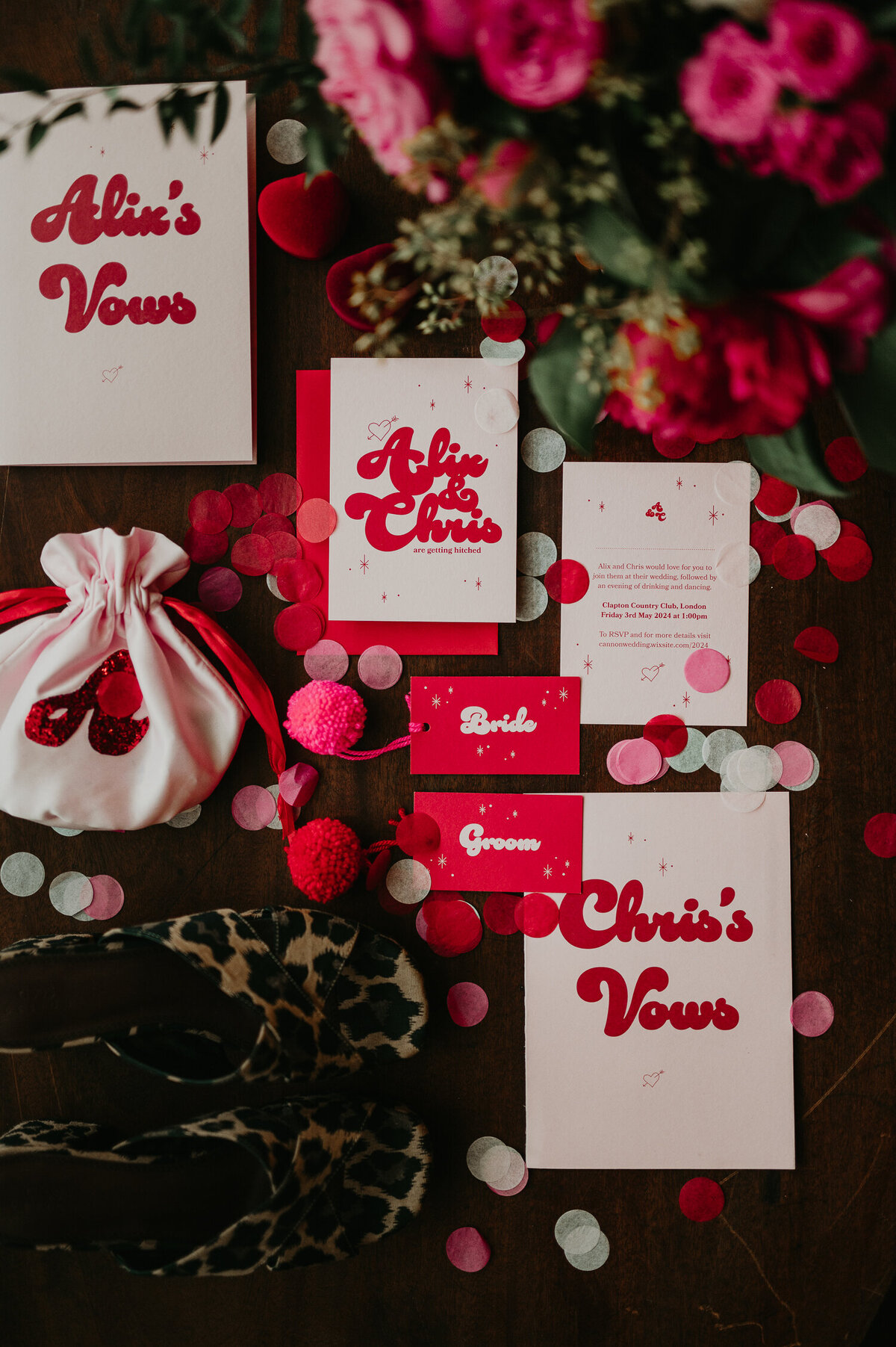 Pink and red wedding stationery flat lay on a table at Clapton Country Club in London.
