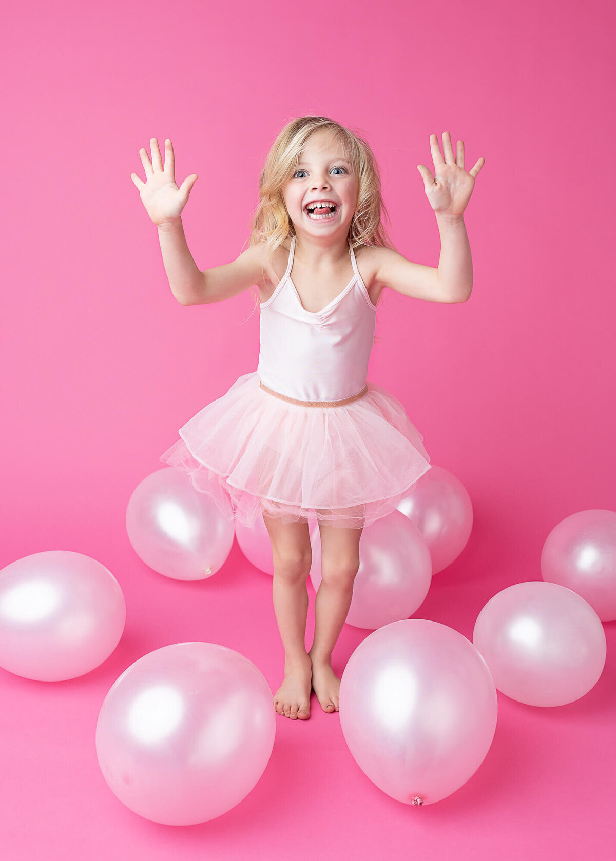 girl in pink tutu on pink background with pink balloons