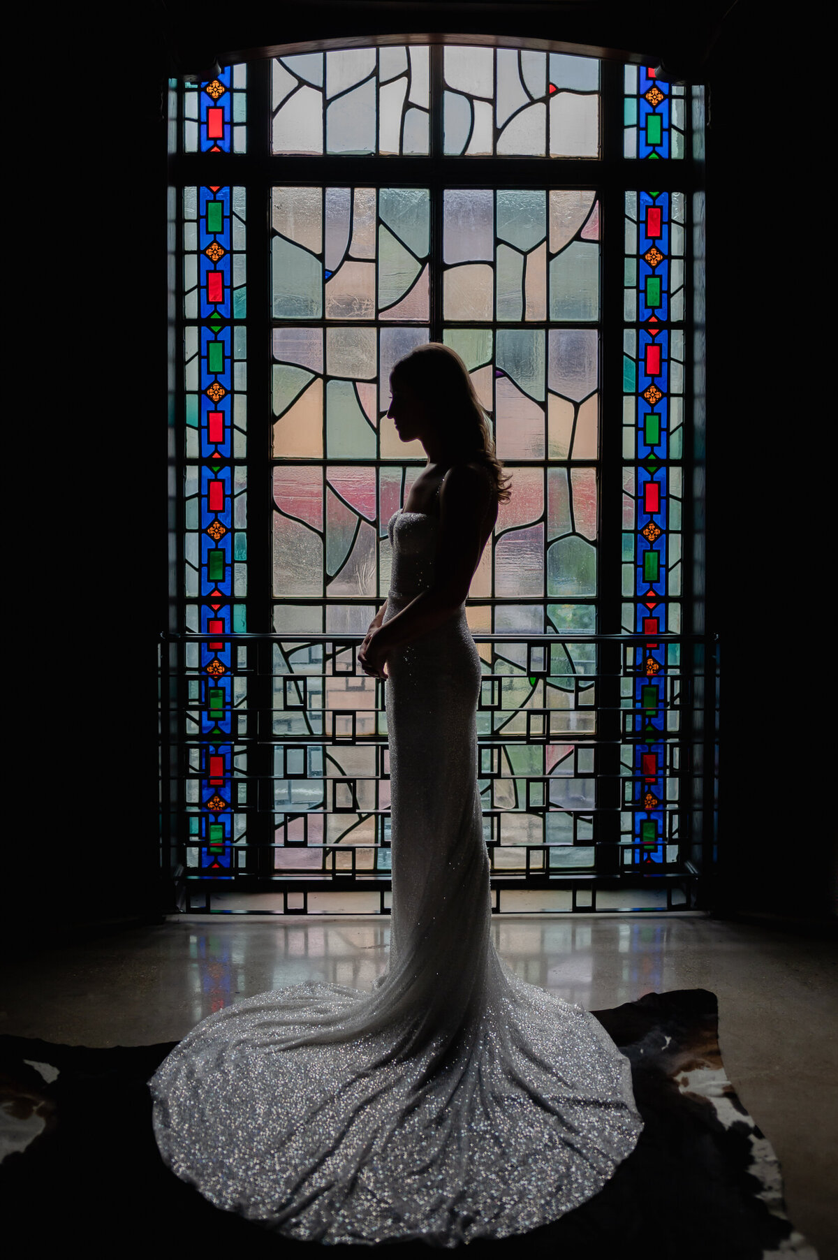 Bride is silhouetted in front of at stained glass window at Revel Motor Row