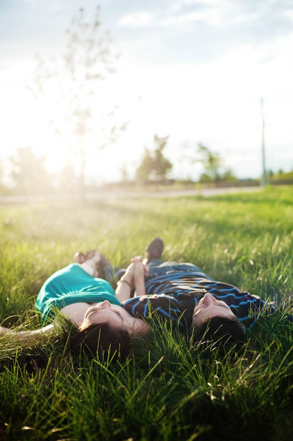 a man and woman lay in the grass drenched in sunshine