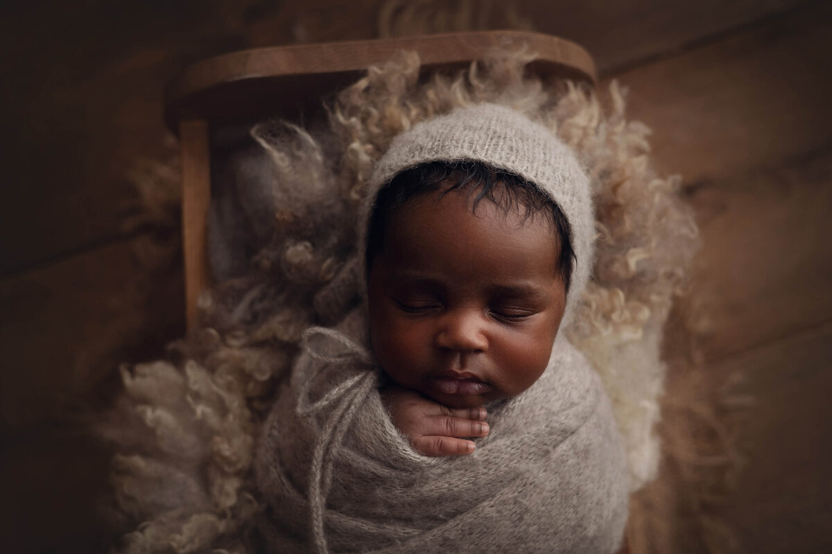 african american newborn baby in cradle on wood background