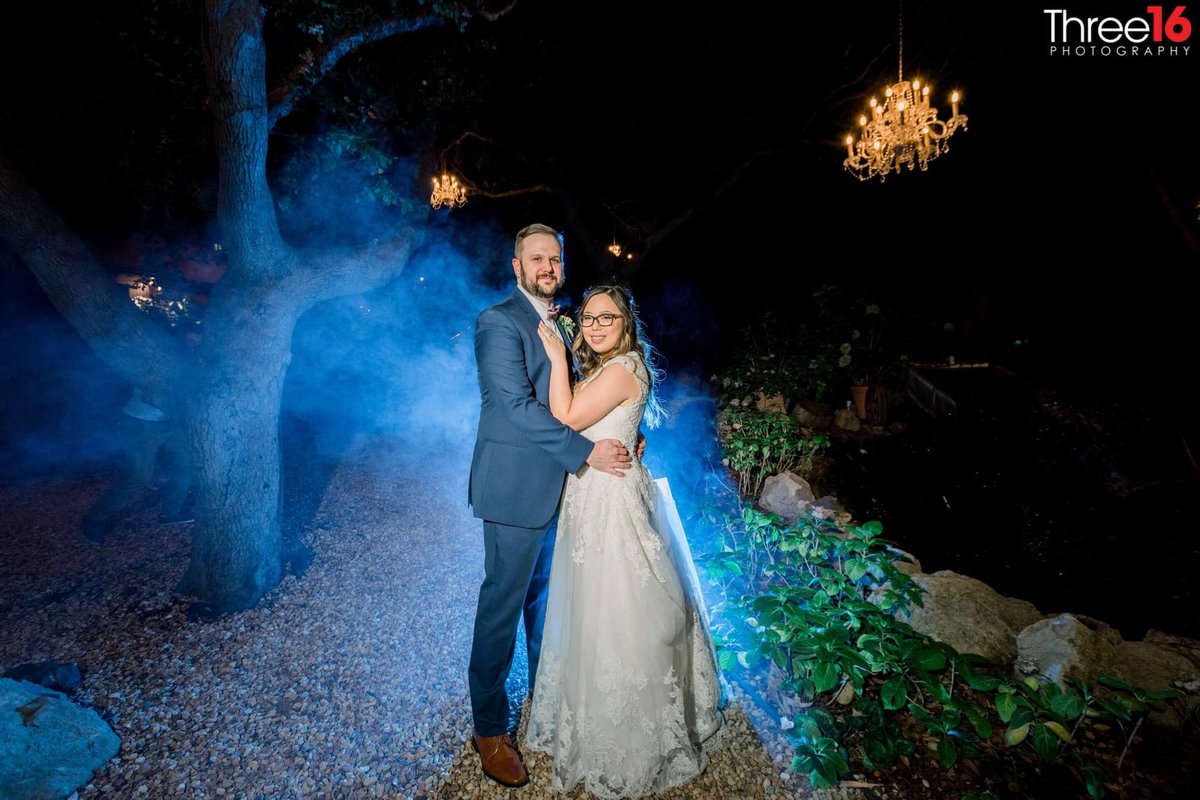 Bride and Groom pose for photos at night with blue highlight behind them