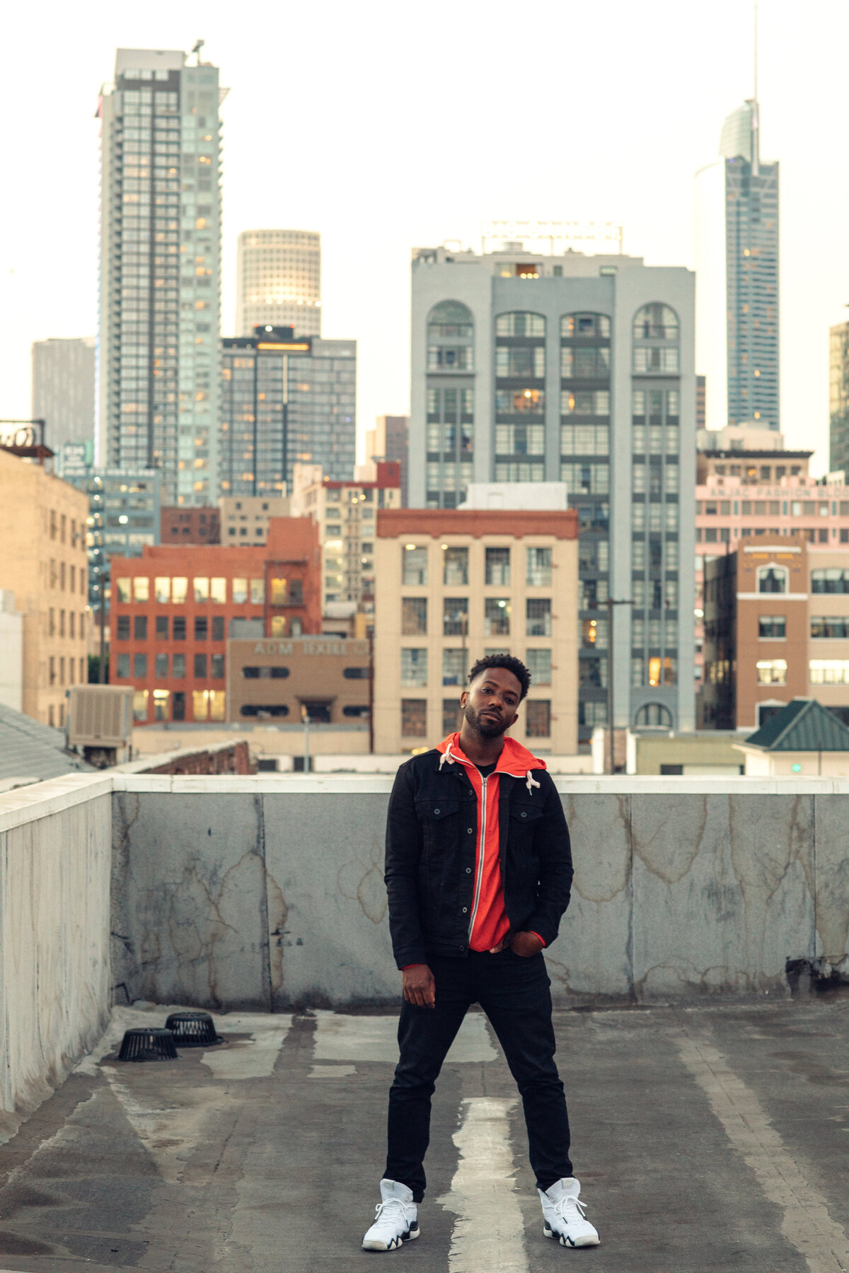 Portrait Photo Of Young Black Man In Orange Hoodie Standing At a Rooftop Los Angeles