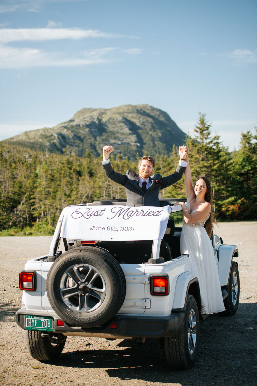 bride and groom in white jeep with just married sign after eloping on summit of mount mansfield in stowe vermont