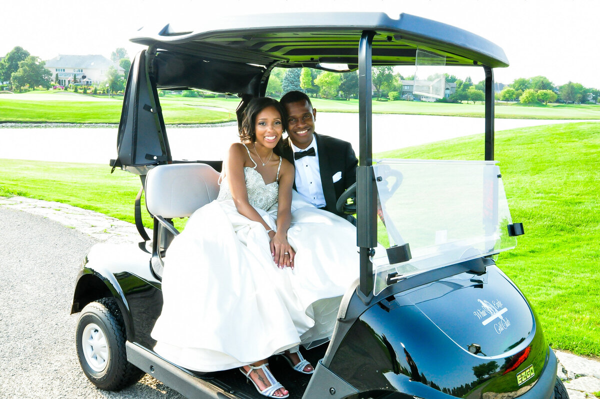 Bride and groom riding a gold cart