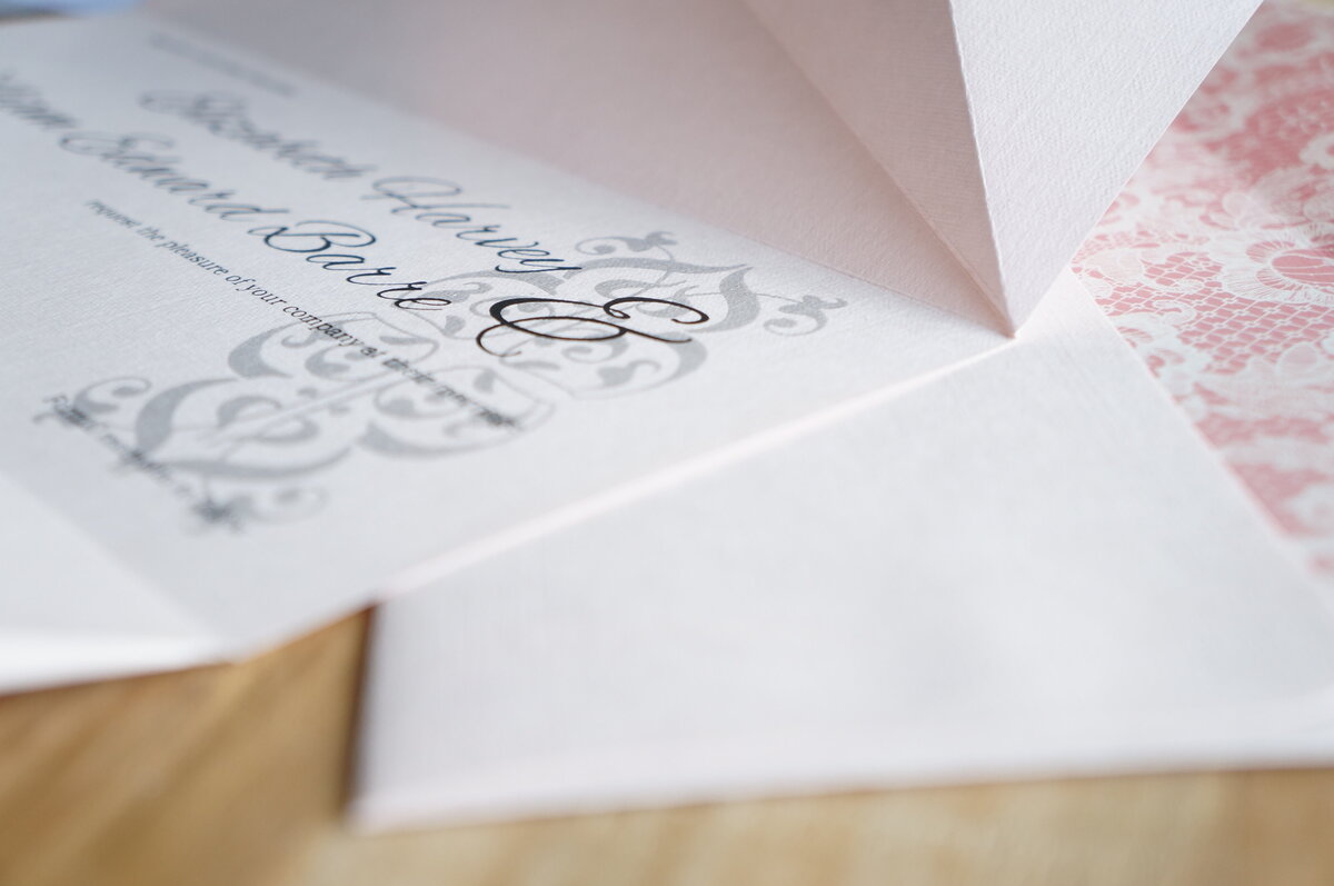 Elegant origami wedding invitation with large ampersand and pink paper and envelope