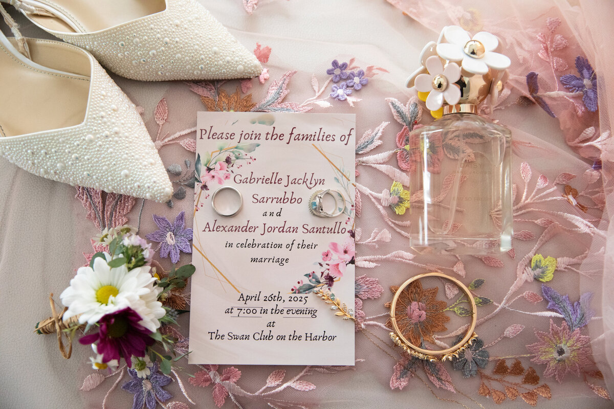 Flat lay still life of pink wedding details including shoes invitation perfume flowers and jewelry Swan Club Long Island New York wedding photographer Milestone Images