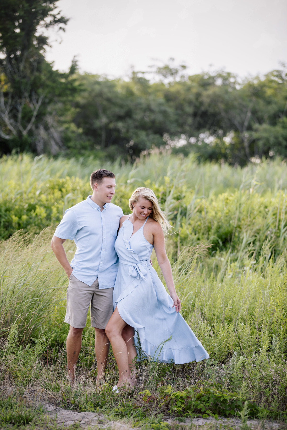 engaged couple stand in tall grass in manasquan nj