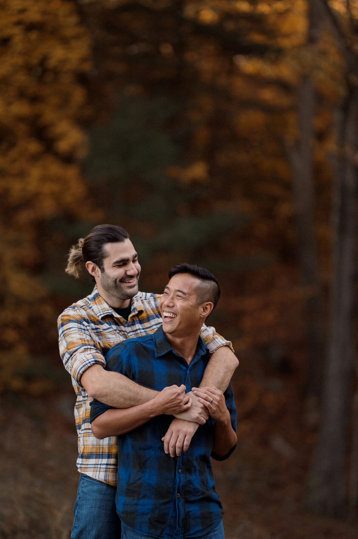 two men engagement session at a lake in the woods on a fall day. a gay couple and lgbtw friendly session. featuring a white man and asian man.