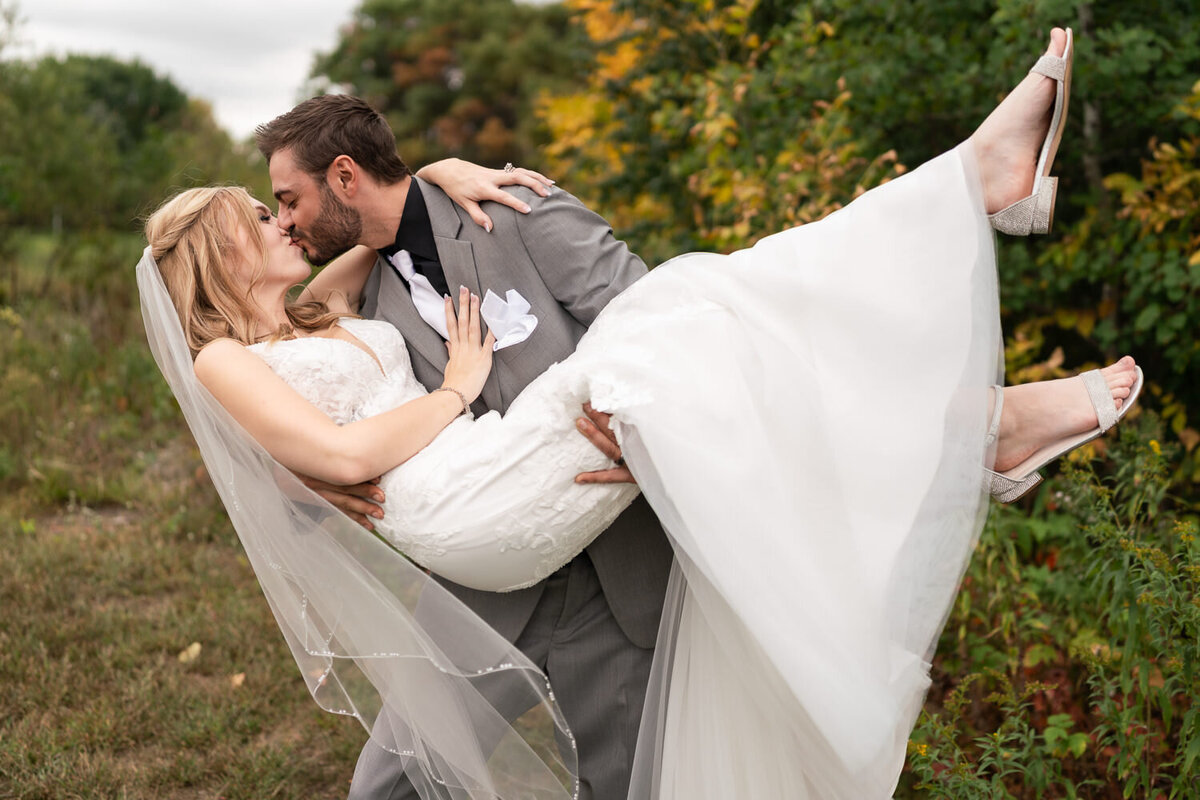 Groom lifts and kisses bride on rainy day.