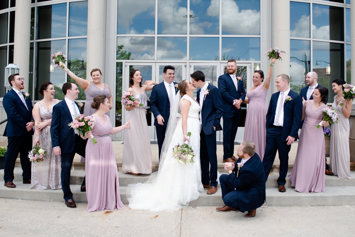 A wedding party cheering on as a couple shares a kiss