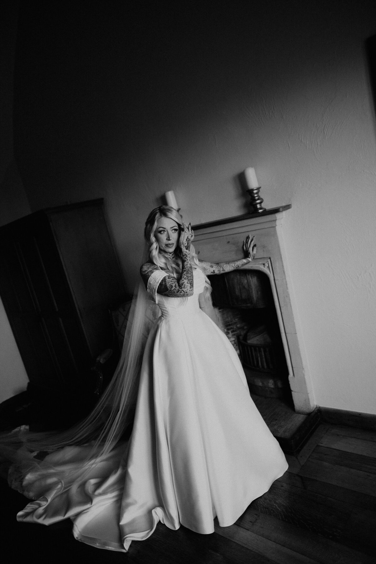 Tattooed Bride stands in the window light before her wedding ceremony at Lympne Castle in Kent.