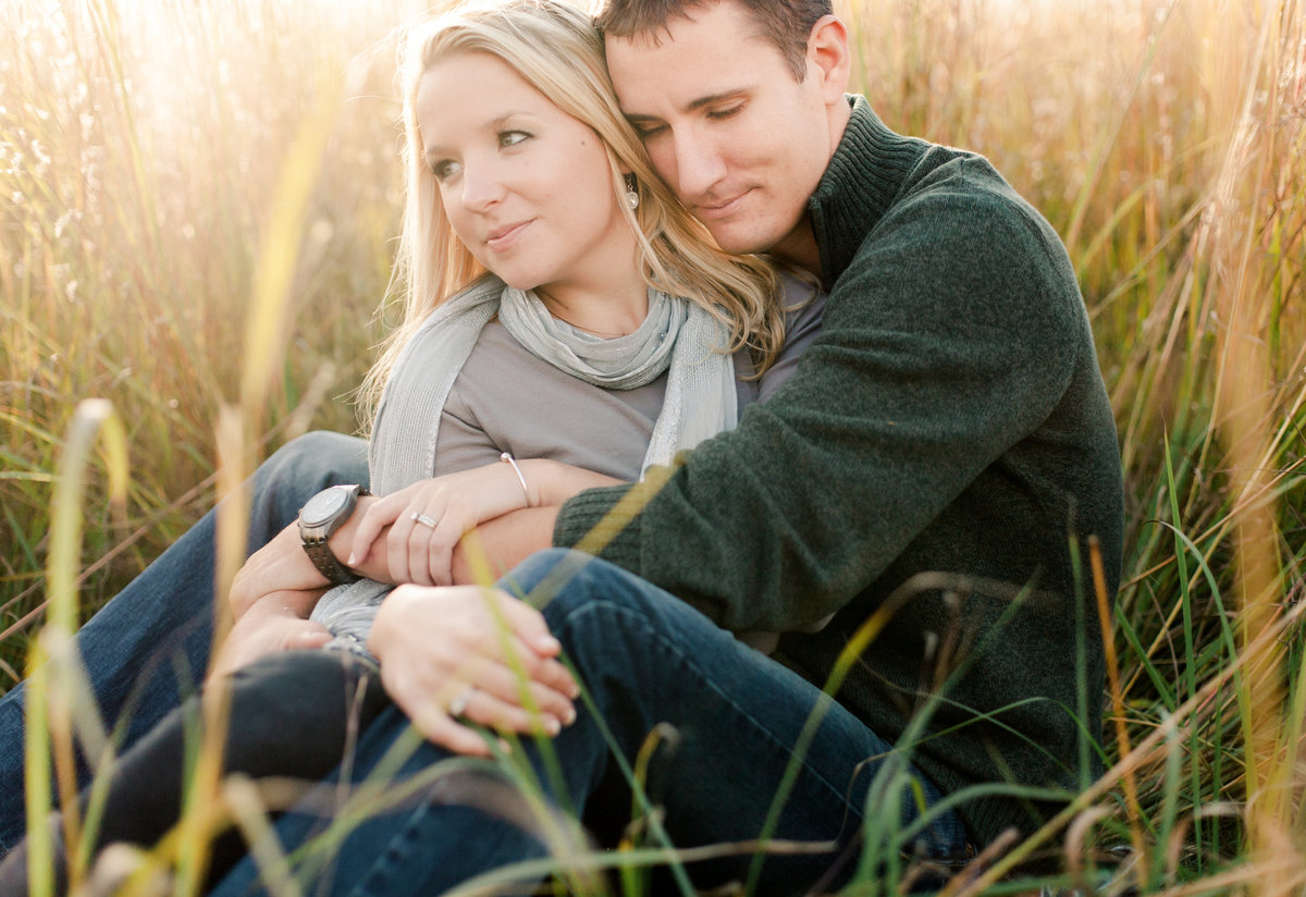 couple cuddles in fall grasses of chester woods state park for engagement photography