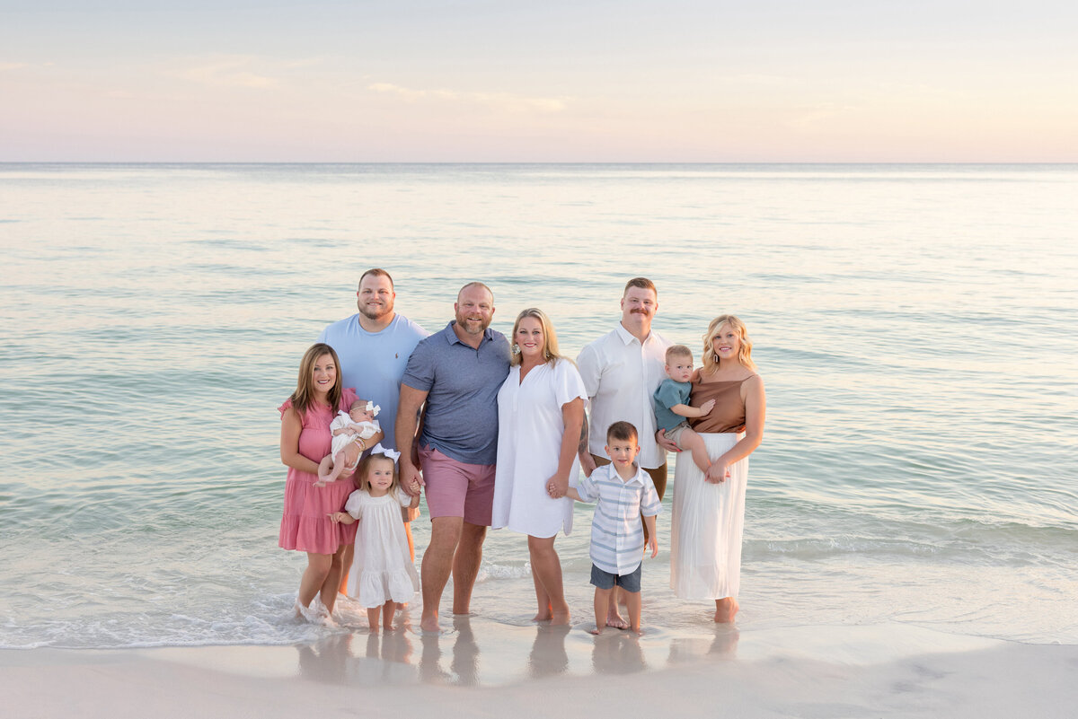 An extended family standing in shallow water at the beach