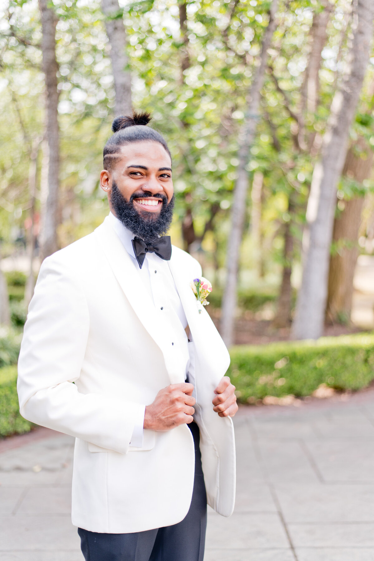 Smiling groom standing with white tuxedo at Fort Worth wedding