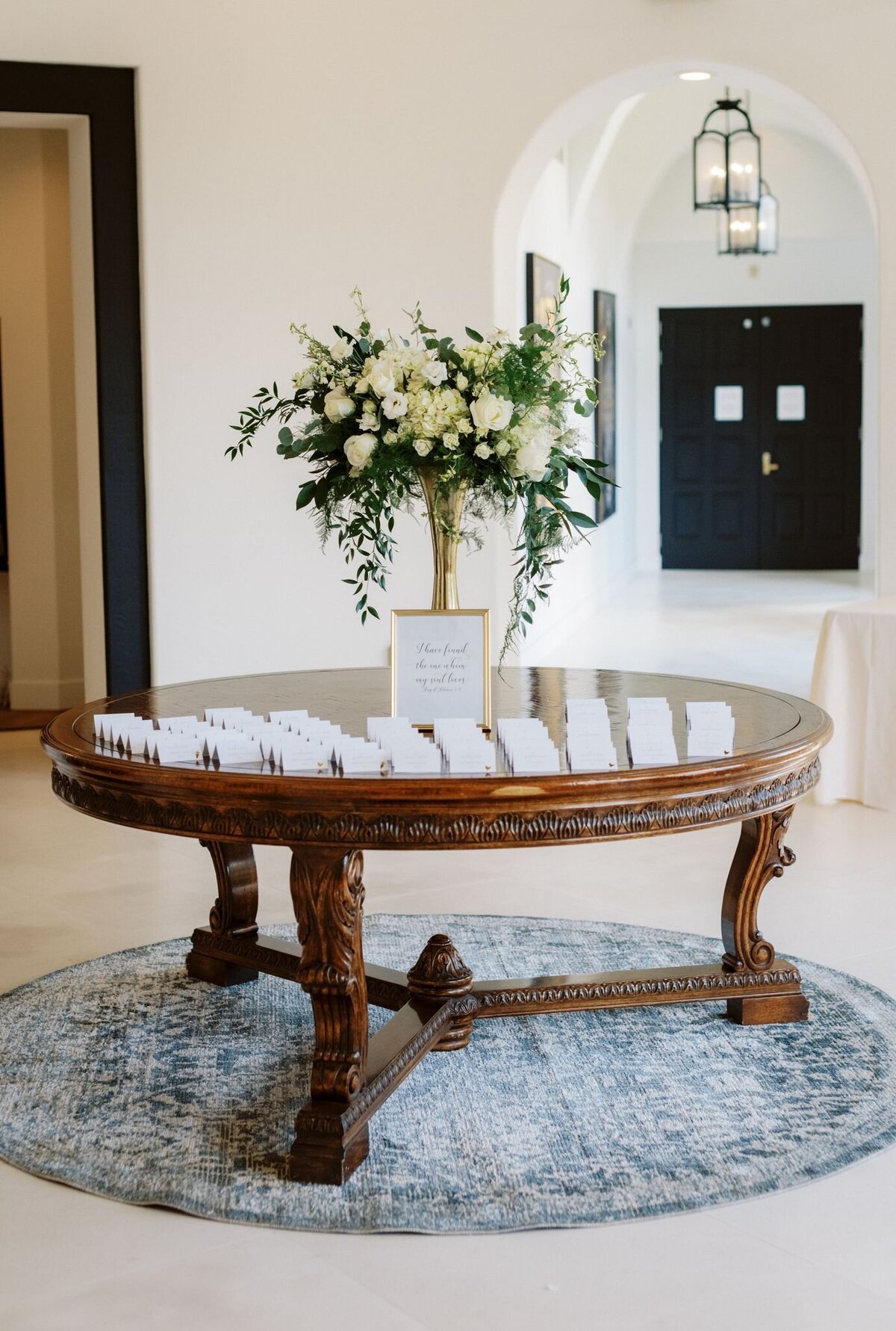 A minimalist bouquet sits next to the seating arrangements for the wedding reception.