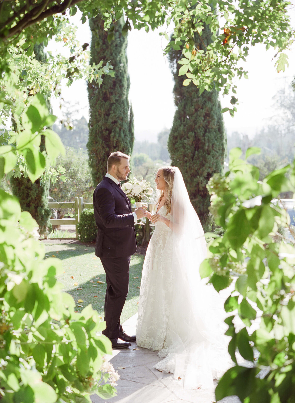 Classy bride and groom take center stage at a pleasant, green garden and hold hands.