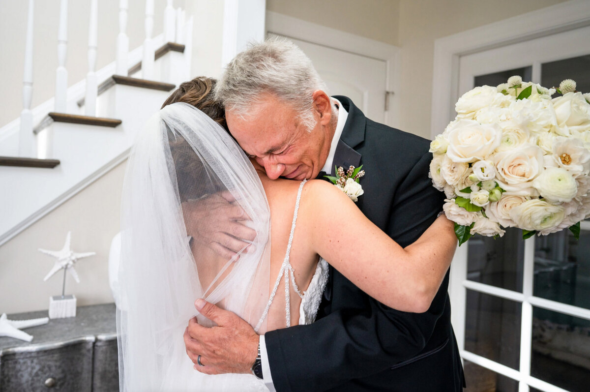 Father, crying while holding his daughter after seeing her for the first time in her wedding gown before her ceremony at the yacht club of Stone Harbor