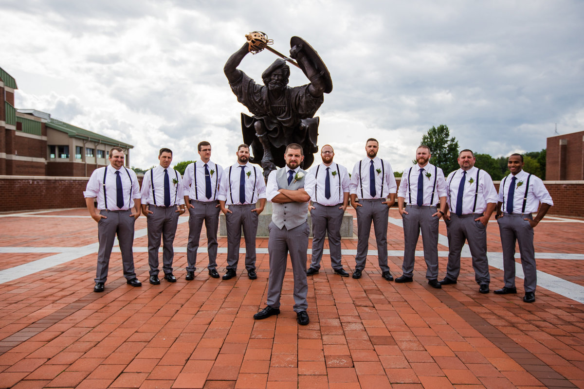 Groom and groomsmen pose in front of Angus statue on the campus of Edinboro University