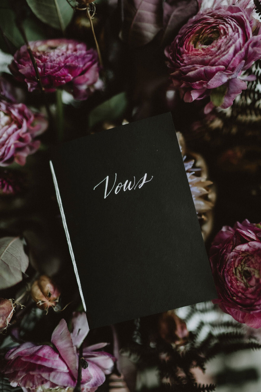 Black vow book on pink flowers