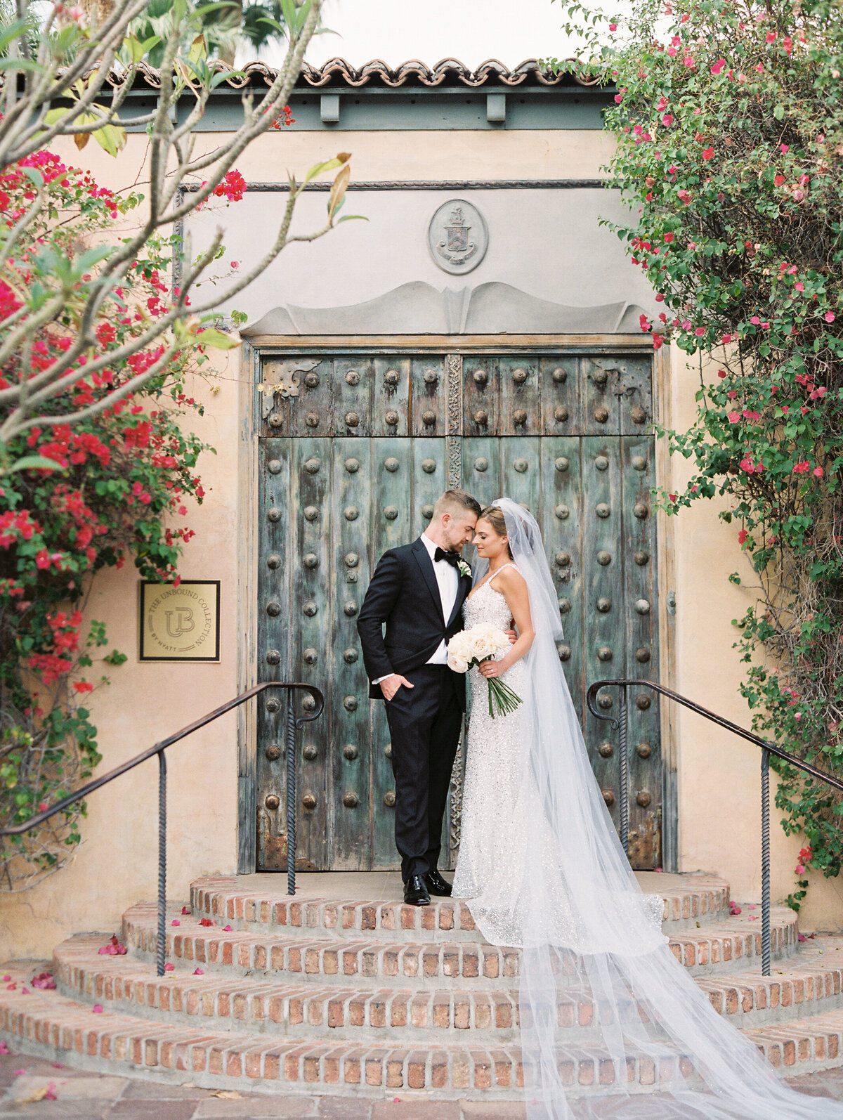 bride and groom standing in front of doors and the royal palms resort in arizona