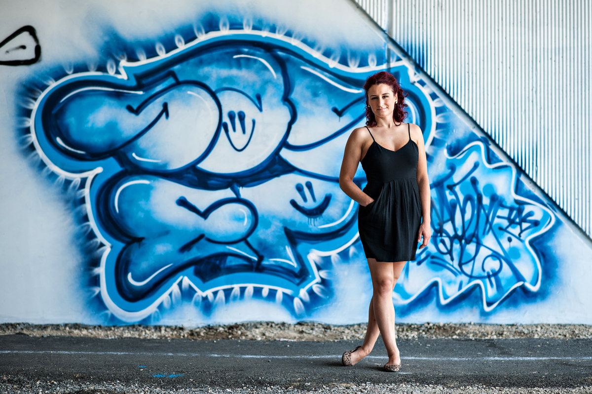 portrait of a dancer in front of a blue graffiti wall.