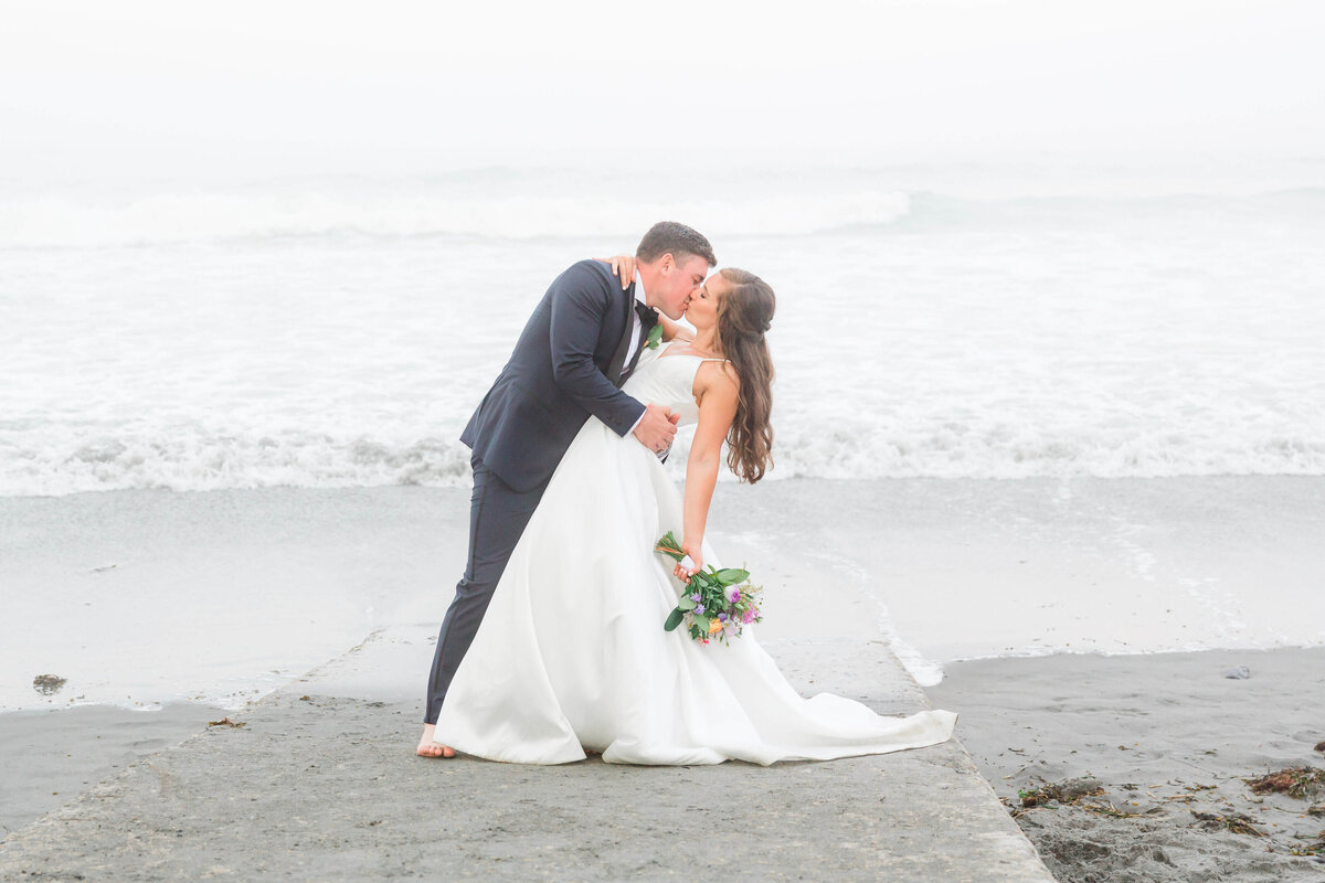 adventurous bride and groom standing on rocks at York Harbor beach for york Inn Wedding  (28)