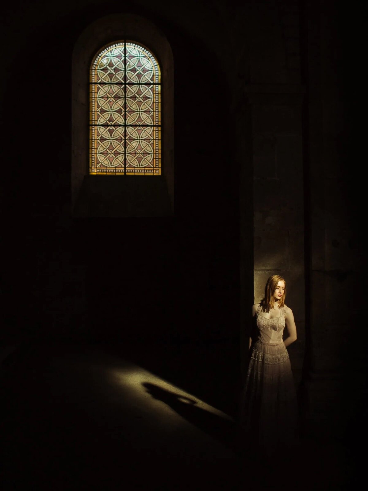 Light shining down on a girl in a dark cathedral.