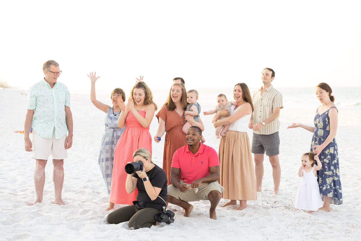 A family celebrating at the beach with a photographer knelt in front of them