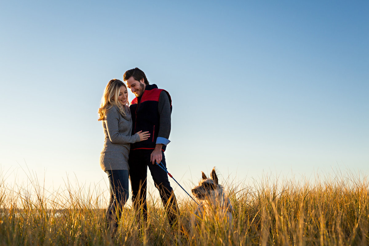 The couple and their dog play in the tall grass on Plum Island MA