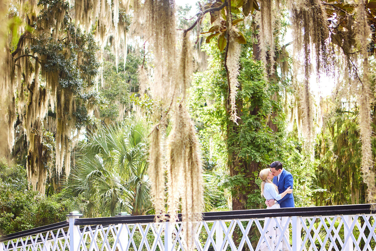 Couple kisses on Long White Bridge at Magnolia Plantation and Gardens Engagement Session Charleston Wedding Photographer