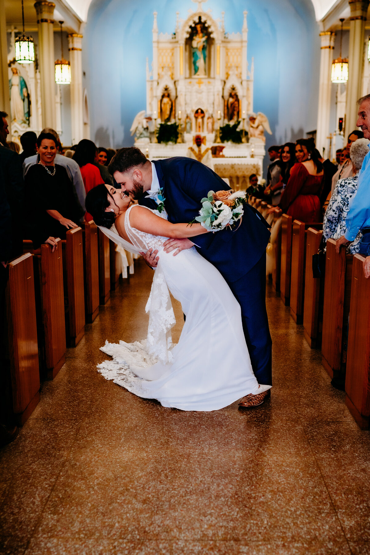 groom dips bride for kiss in catholic church in Delcambre, la